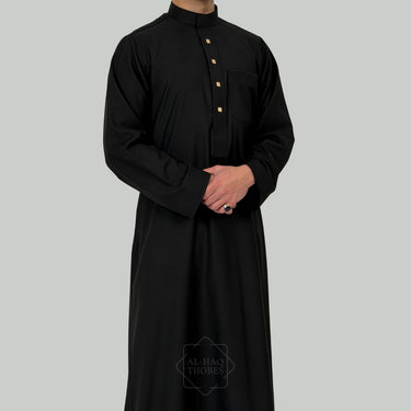 model in a Black collared thobe with gold buttons on a gray background