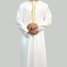 Model wearing a White collarless omani thobe with sophisticated gold embroidery on a plain background.