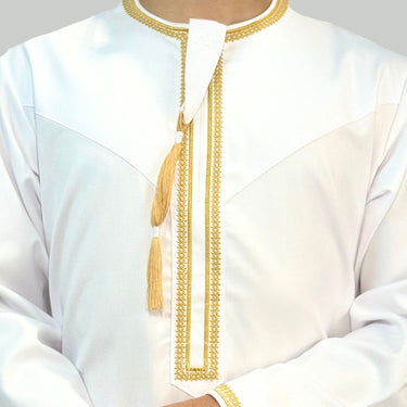 Model wearing a White collarless omani thobe with sophisticated gold embroidery on a plain background.